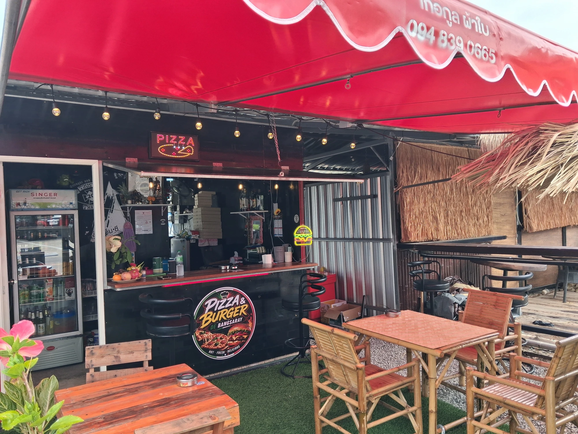 Terrasse du restaurant Pizza & Burger Bang Saray avec tables en bois et toit de chaume